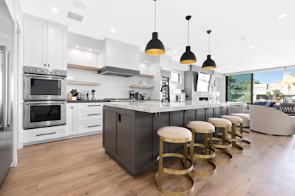 Waterside's airy kitchen, featuring open shelving, white cabinetry, and a full wine fridge, is ideal for those inspired by Newport Beach’s culinary scene.