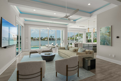 Sophisticated living room with coffered ceiling, dark wood floors, and a sweeping water view in a Marco Island luxury residence, capturing the elegance and tranquility of coastal living.