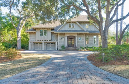 Seaside home in South Carolina, front of home and driveway flanked by mature trees. 