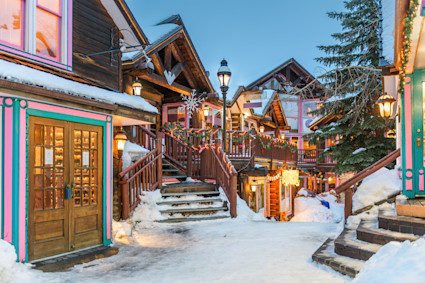 A snowy evening on a historic street in Breckenridge, Colorado, with buildings lit up, capturing the town's welcoming winter spirit.