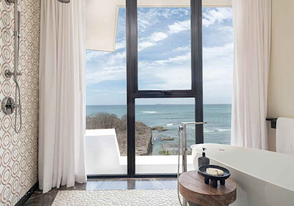 Bathroom with views of the ocean with large luxurious soaking tub and open-air shower. 