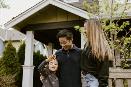 A family stands in front of a home while considering “Is now the time to buy a house?”
