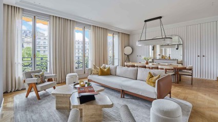 A well-furnished living room of a Paris vacation home featuring a plush couch, elegant chairs and a table, perfect for relaxation and gatherings