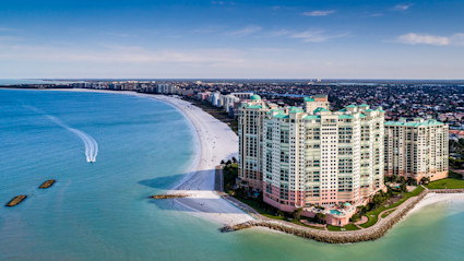 A captivating aerial view of Marco Island’s coastline, featuring luxurious beachfront condos, pristine white sand, and turquoise waters. This image encapsulates the serene and upscale beach lifestyle found on Florida’s Gulf Coast.