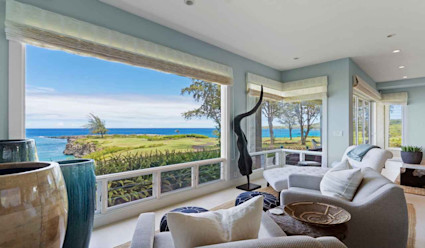 Living area with several armchairs facing a large window with a panoramic view of the coast.