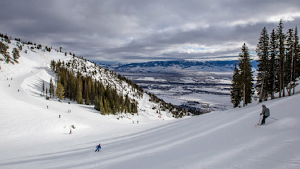 Skiers on a steep slope on a cloudy day.