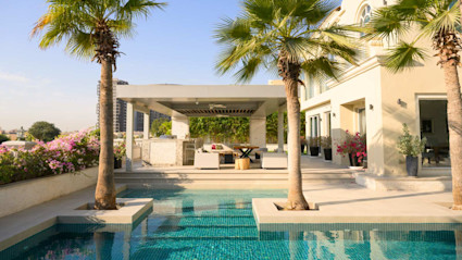 Image of a luxury home with a pool and palm trees. 
