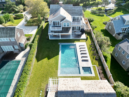 a stunning aerial view of a Nantucket second home surrounded by lush greenery, showcasing the exclusivity and serenity of an idyllic island escape
