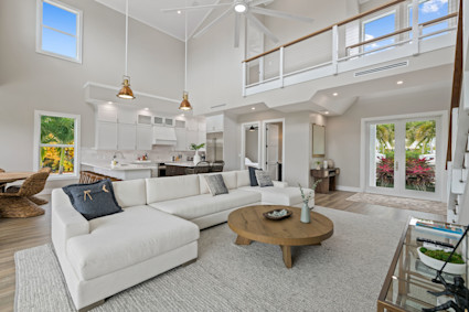A sunlit living room with high ceilings and hardwood floors in The Keys, FL, highlighting a seamless blend of luxury and private access to the natural surroundings.