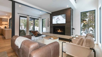 Living room of a Squaw Valley second home with a modern fireplace, plush furniture, forest views and plenty of spaces to relax and dine