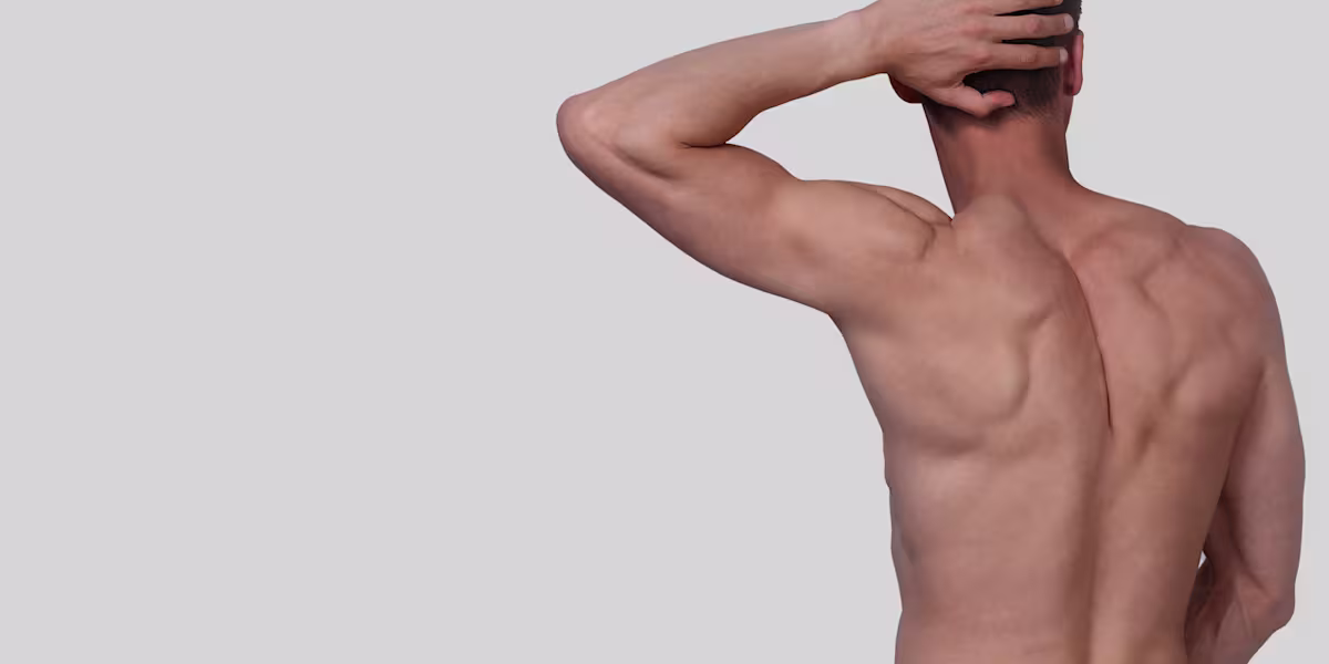 Shirtless man poses in front of a white wall