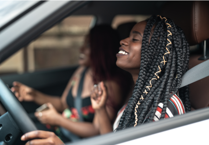 Duas mulheres sorrindo sentadas dentro de um carro.