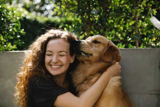 Chica sonriente abrazando a un labrador