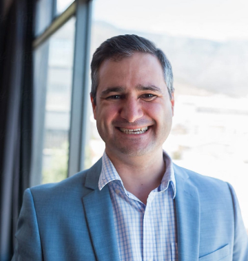 Nell'immagine è raffigurato un uomo maturo, vestito in giacca e cravatta, che sorride.