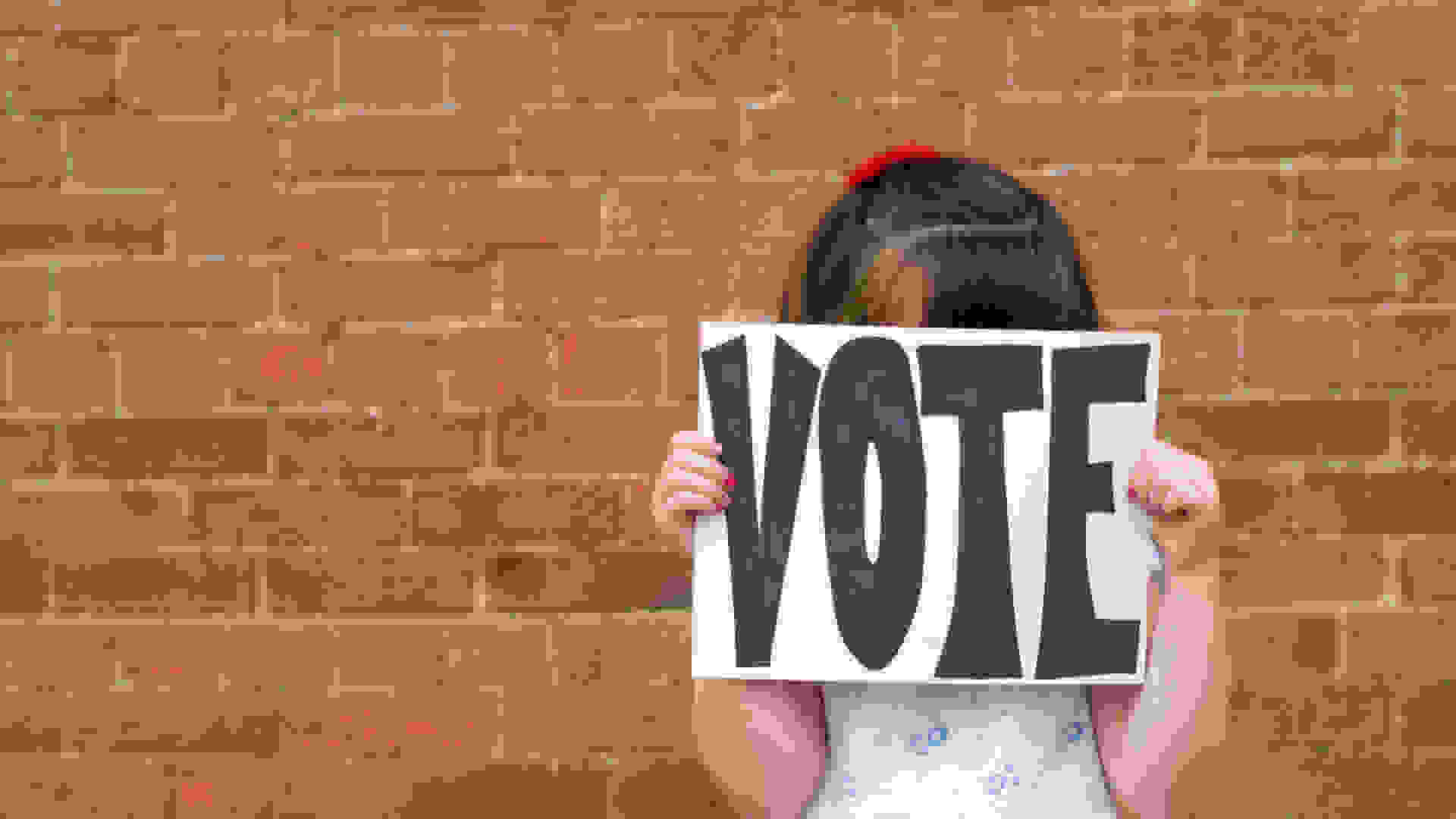 School child holding a 'Vote' sign