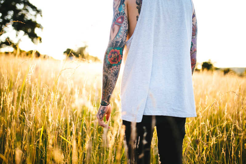 Tattooed man walking in a field