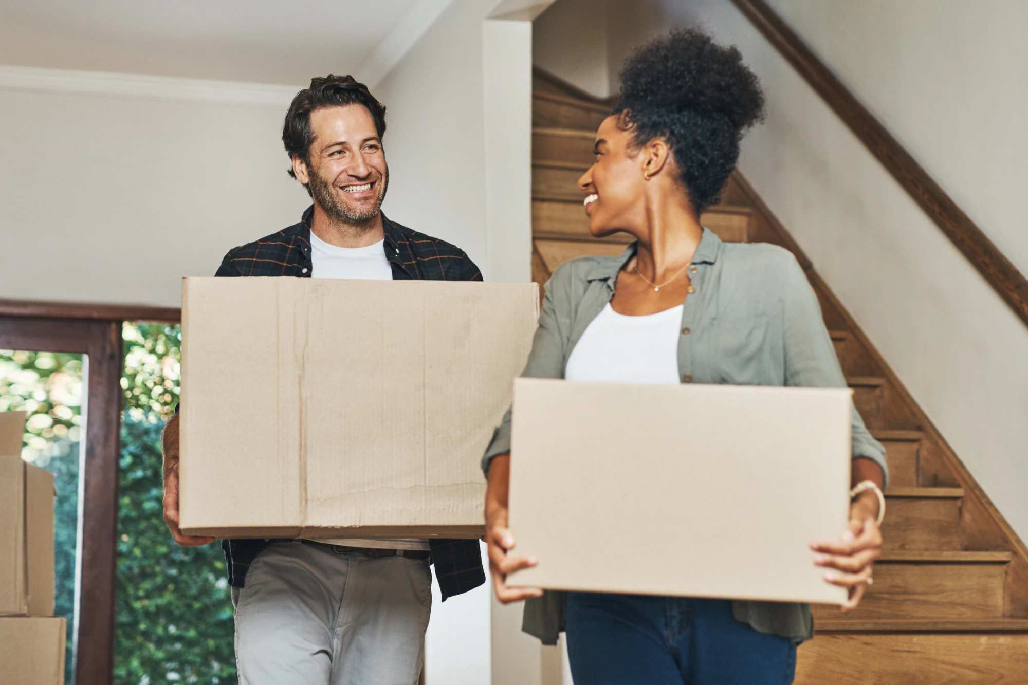 New homeowners moving in with boxes in hands. 