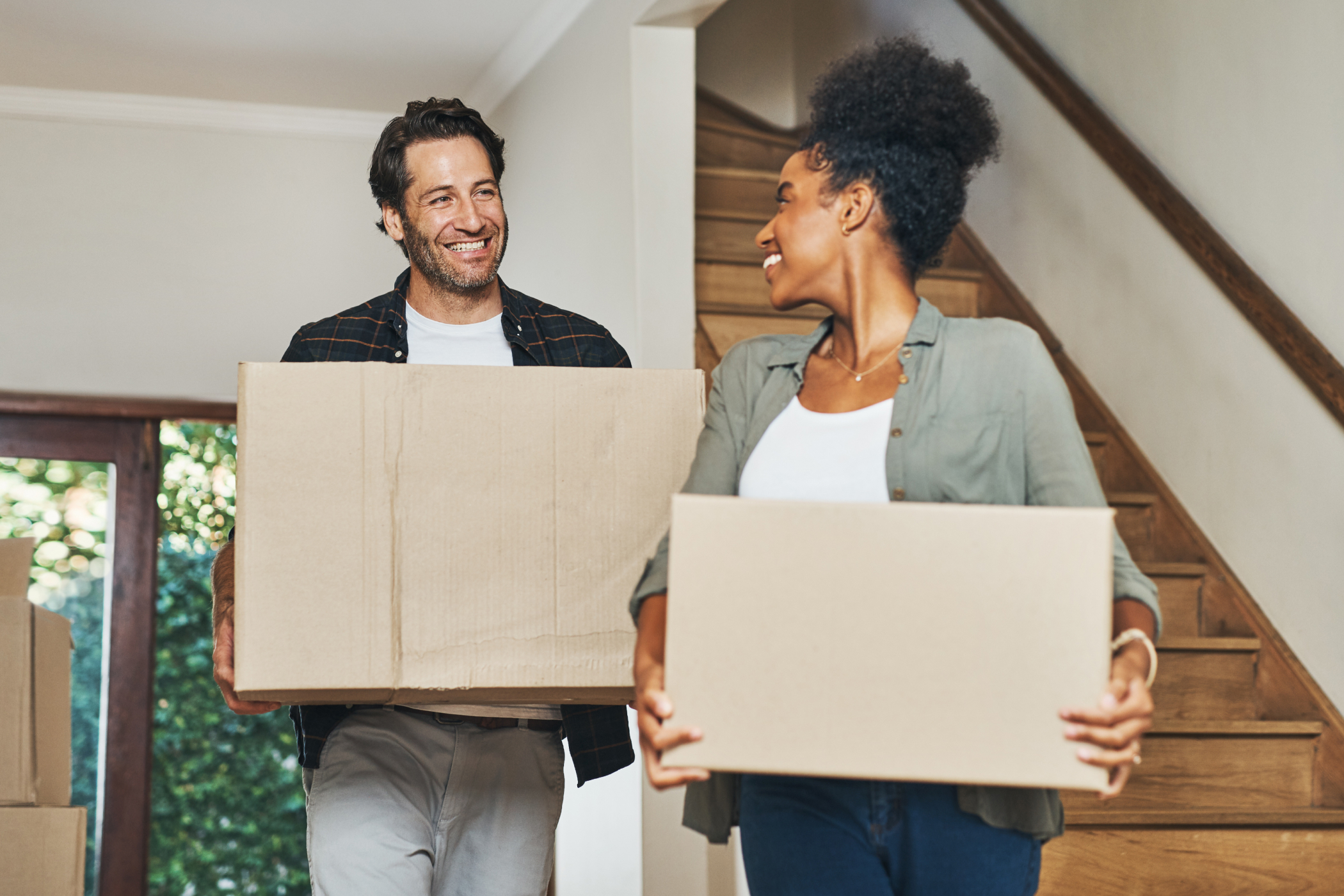 New homeowners moving in with boxes in hands. 