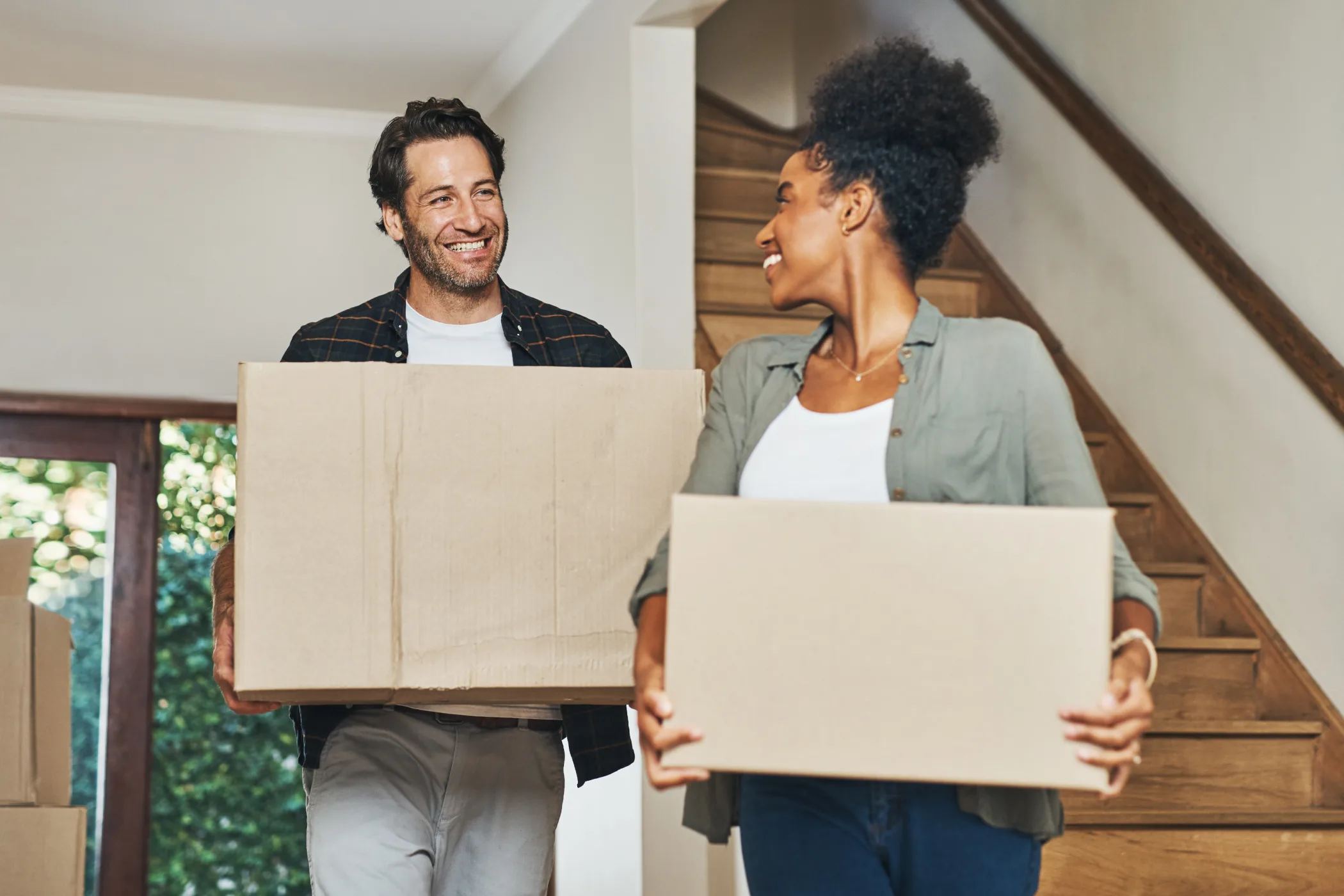 New homeowners moving in with boxes in hands. 