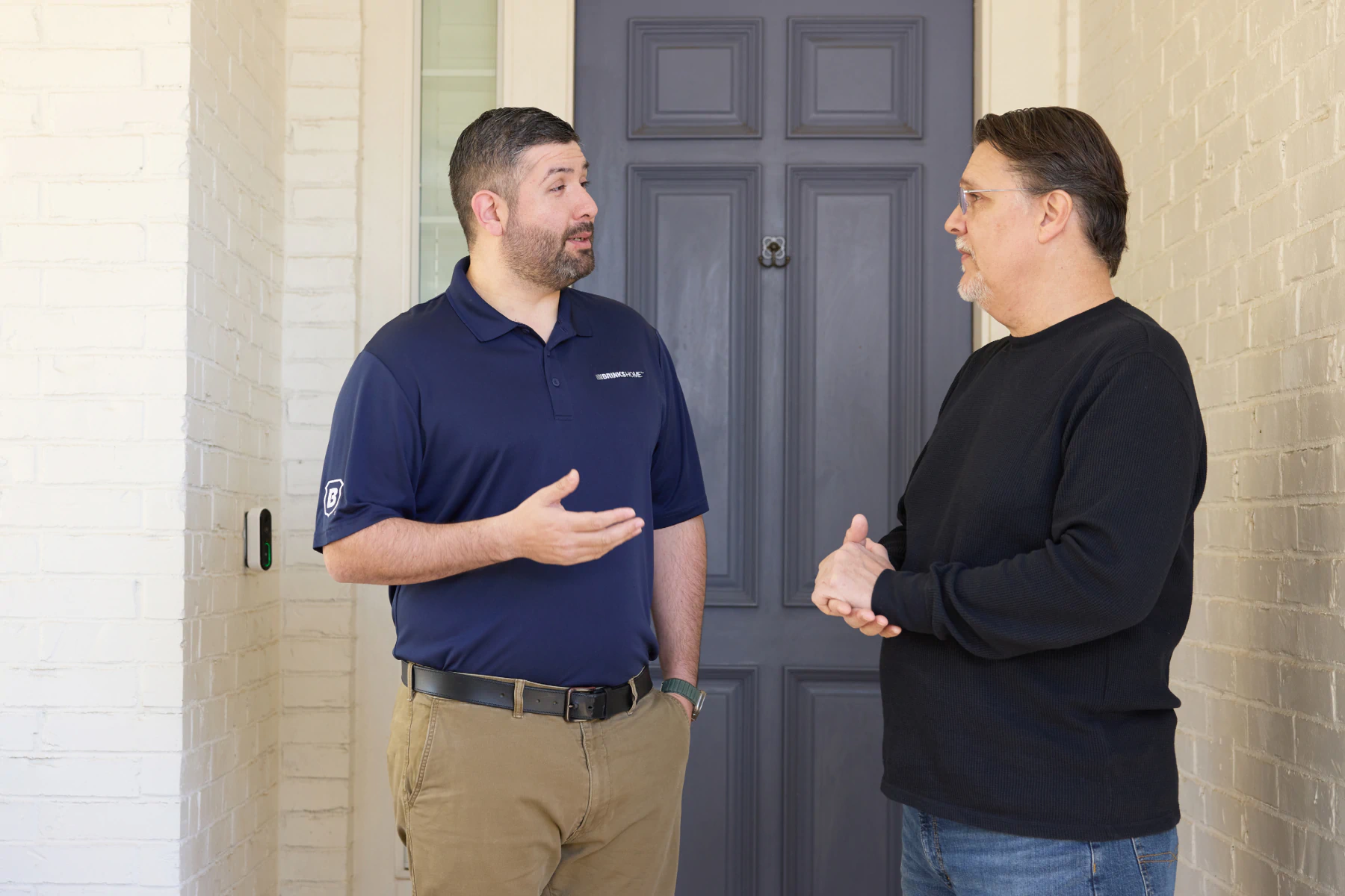 Brinks Home technician speaking with a family caregiver about smart home security options for senior safety.