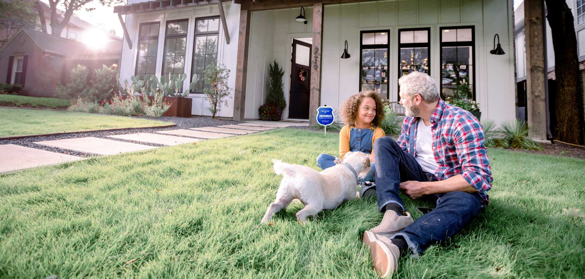 Father and daughter sitting in the front yard of a secure home.