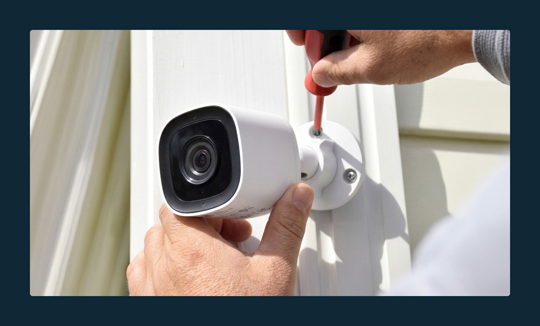 Someone installing an external home security camera.