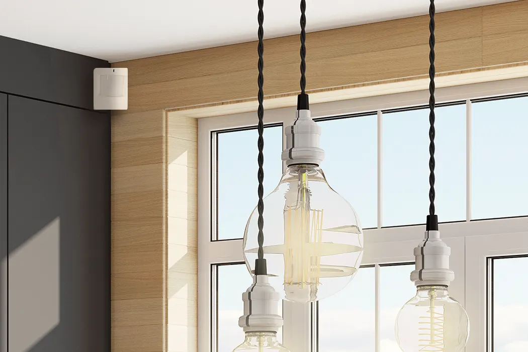A Qolsys motion detector shown in a well-lit room for an article explaining how light might affect traditional motion detectors and the best practices for avoiding false alarms.