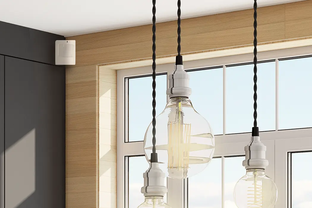 A Qolsys motion detector shown in a well-lit room for an article explaining how light might affect traditional motion detectors and the best practices for avoiding false alarms.
