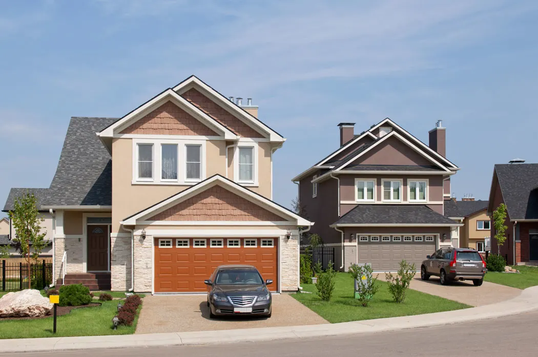 Car in front of the garage of a suburban home. 
