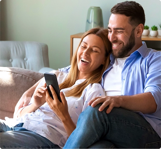 Satisfied customers-couple looking at smart phone to decide from Brinks Home security packages