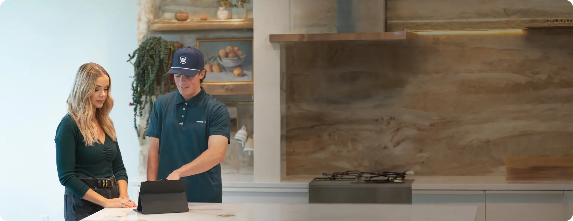 Brinks Home technician walking a homeowner through her smart home security options at the kitchen counter
