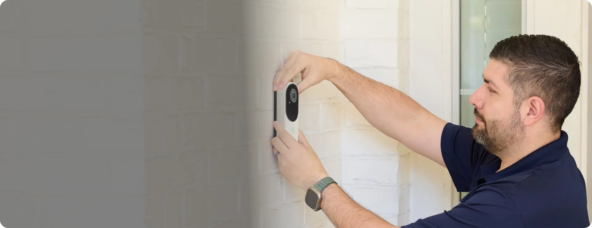 Brinks Home technician installing a video doorbell camera at the front of a home