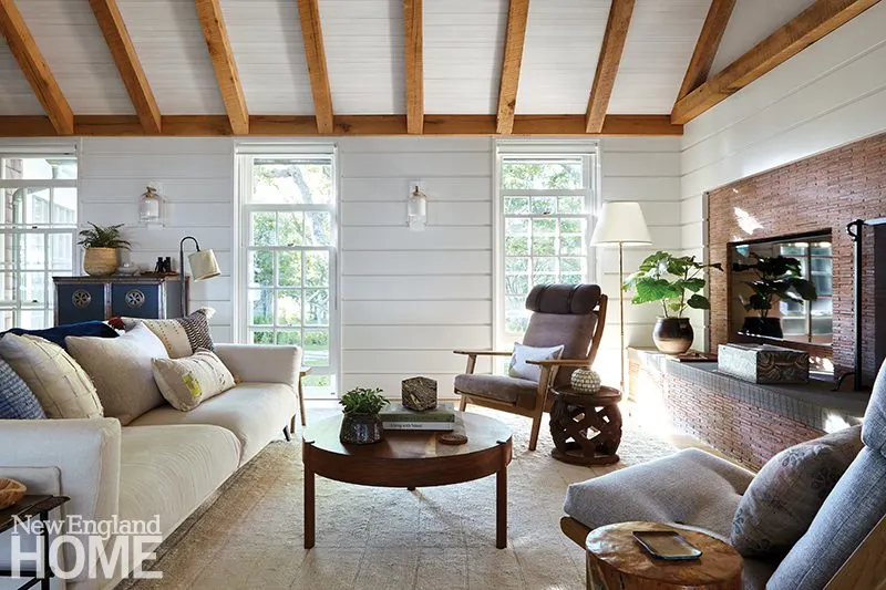 An arflex sofa and vintage Hans J. Wegner chairs harmonize with traditional architectural elements such as the multipaned windows and brick fireplace in the living room.