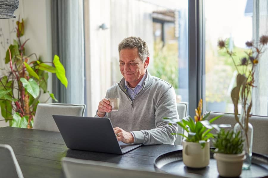 Man aan tafel met laptop