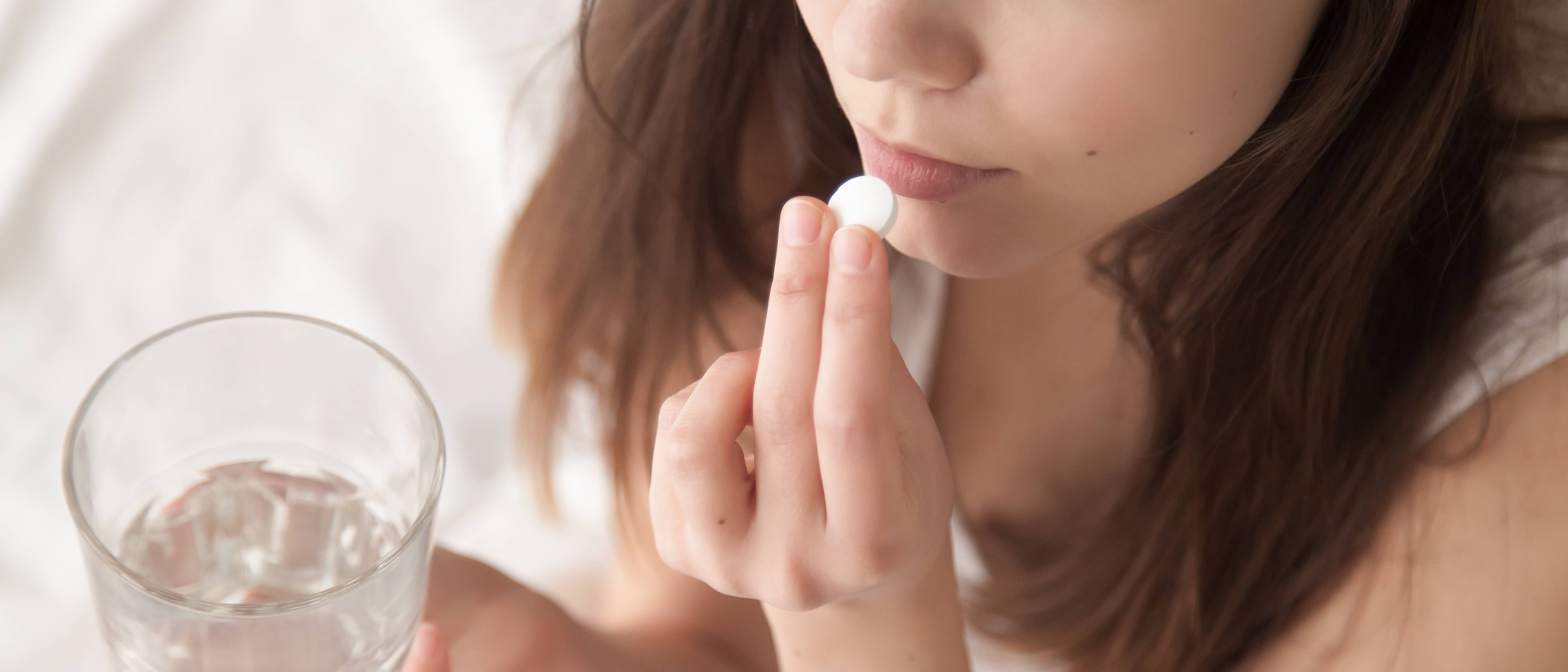 Een vrouw neemt een paracetamol met een glas water 
