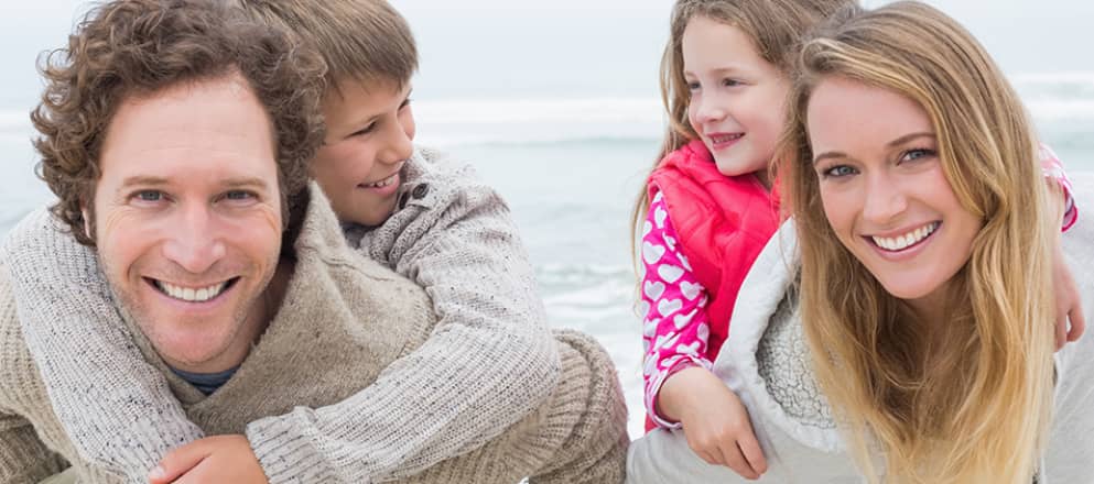 Een gezin loopt lachend over het strand