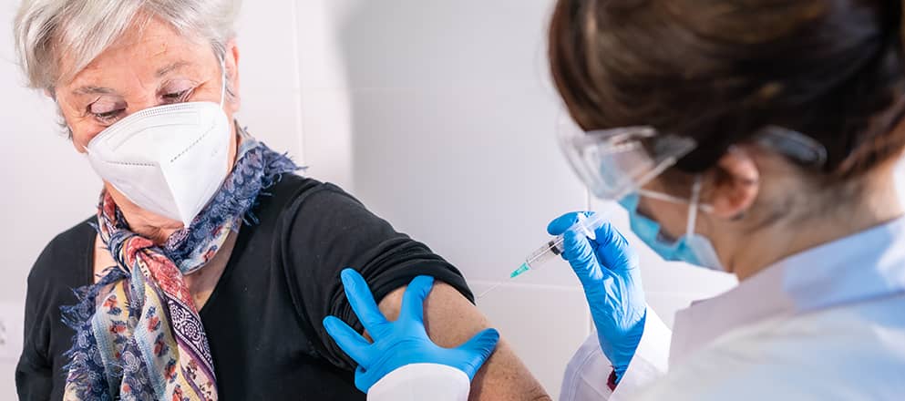 Mevrouw met mondkapje wordt gevaccineerd