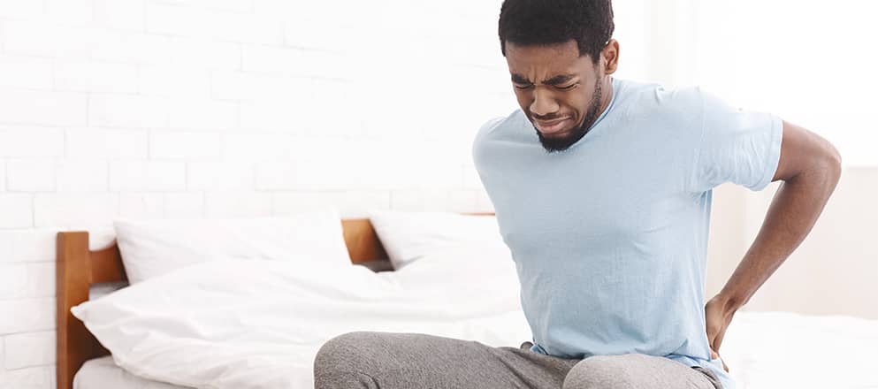 Man met rugpijn staat op uit bed