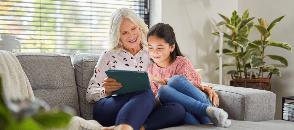 Oma en kleindochter kijken lachend naar tablet
