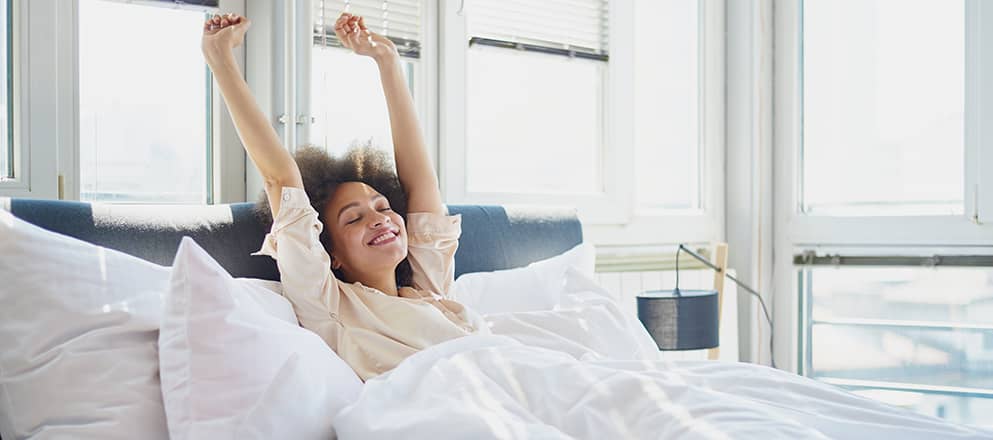 Vrouw rekt zich uit in bed