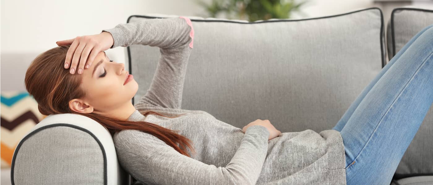 Vrouw ligt met hoofdpijn op de bank