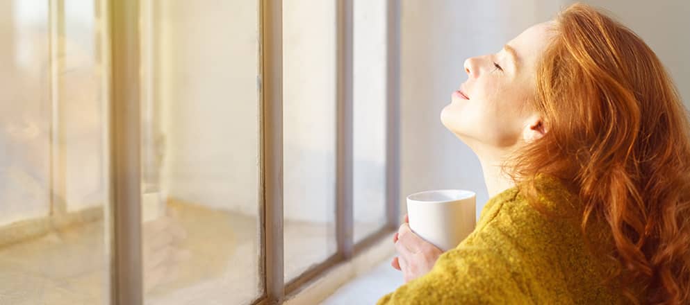 Vrouw die geniet van de zon voor het raam