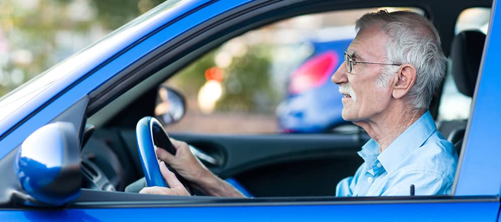 Man zit achter het stuur van een blauwe auto