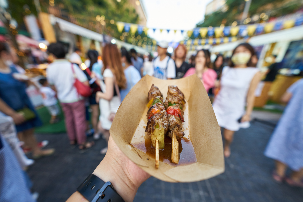 Persona degustando unas banderillas de carne en una feria gastronómica