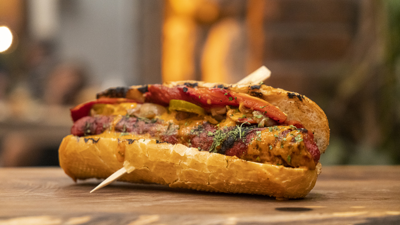 Hot dog gourmet con queso y aderezo de mostaza.