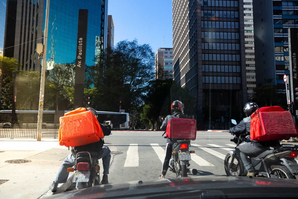 Tres repartidores en moto en la calle