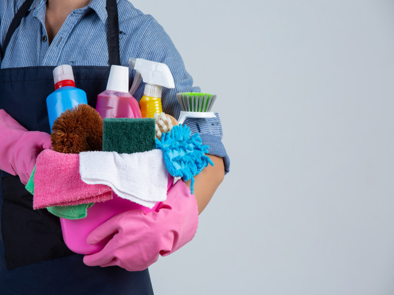 young-girl-is-holding-cleaning-product-gloves-rags-basin-white-wall