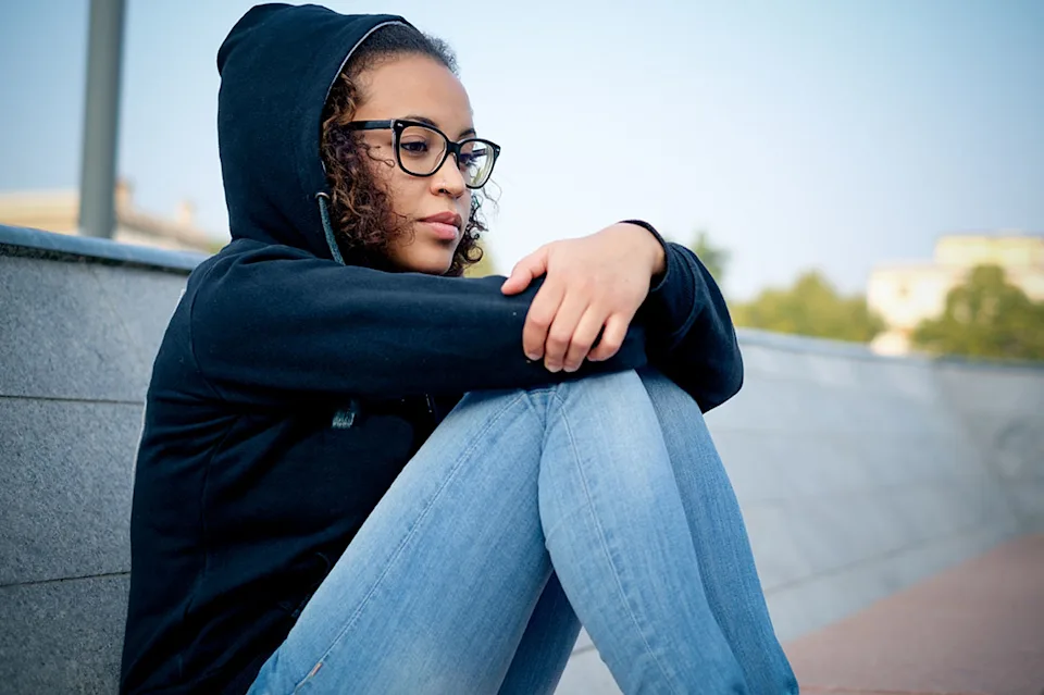 Jeune fille avec des lunettes assise sur le sol