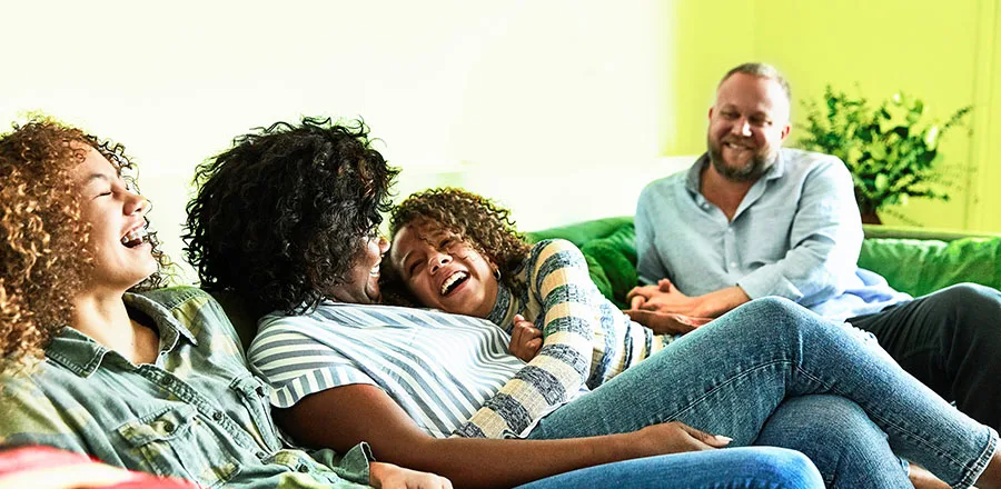 Famille assise sur canapé à la maison rire