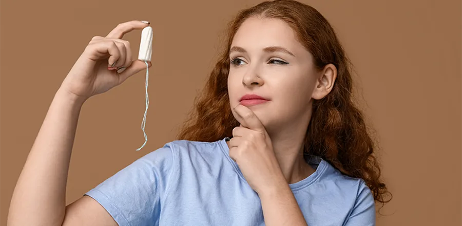 Mão feminina segurando um absorvente interno com aplicador